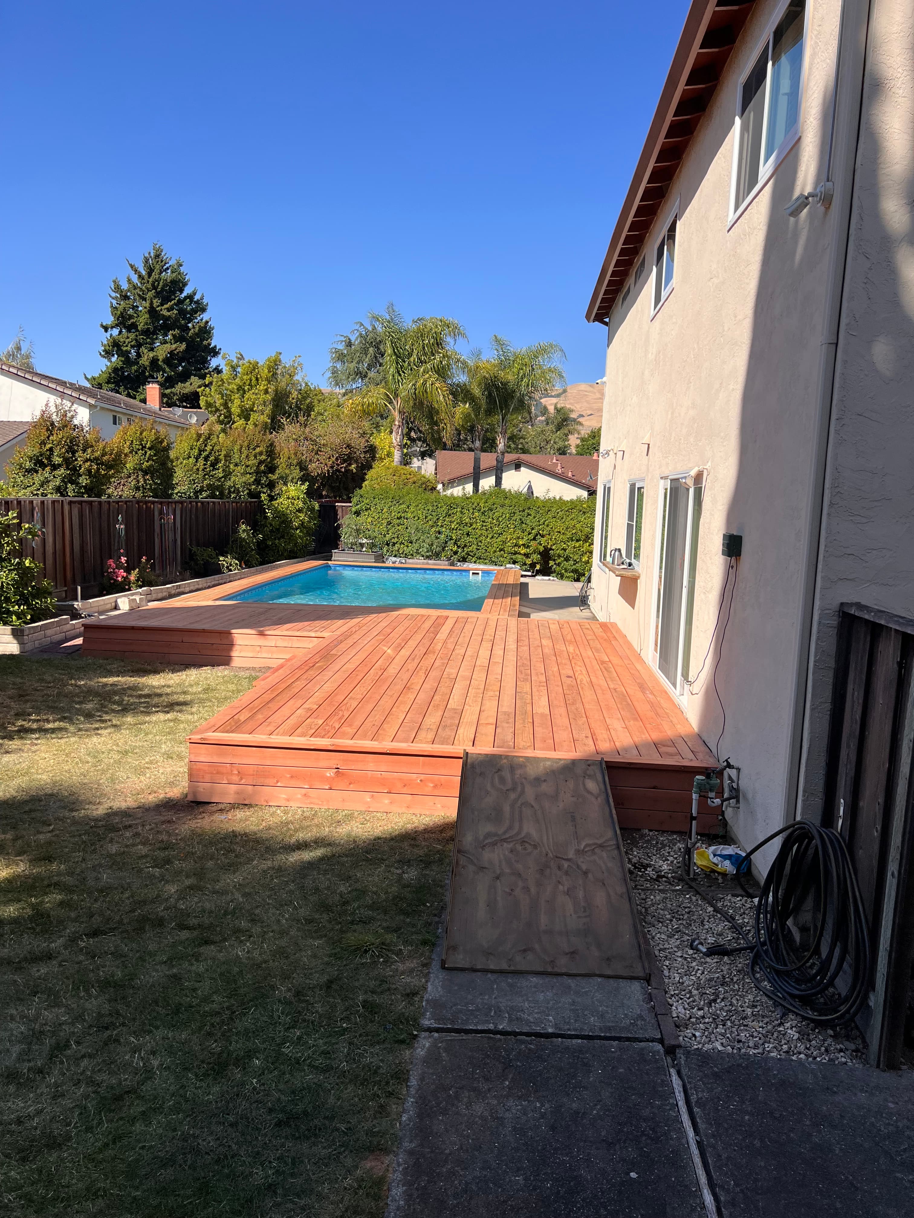 Completed redwood pool deck under blue sky by Far West Builders LLC Bay Area