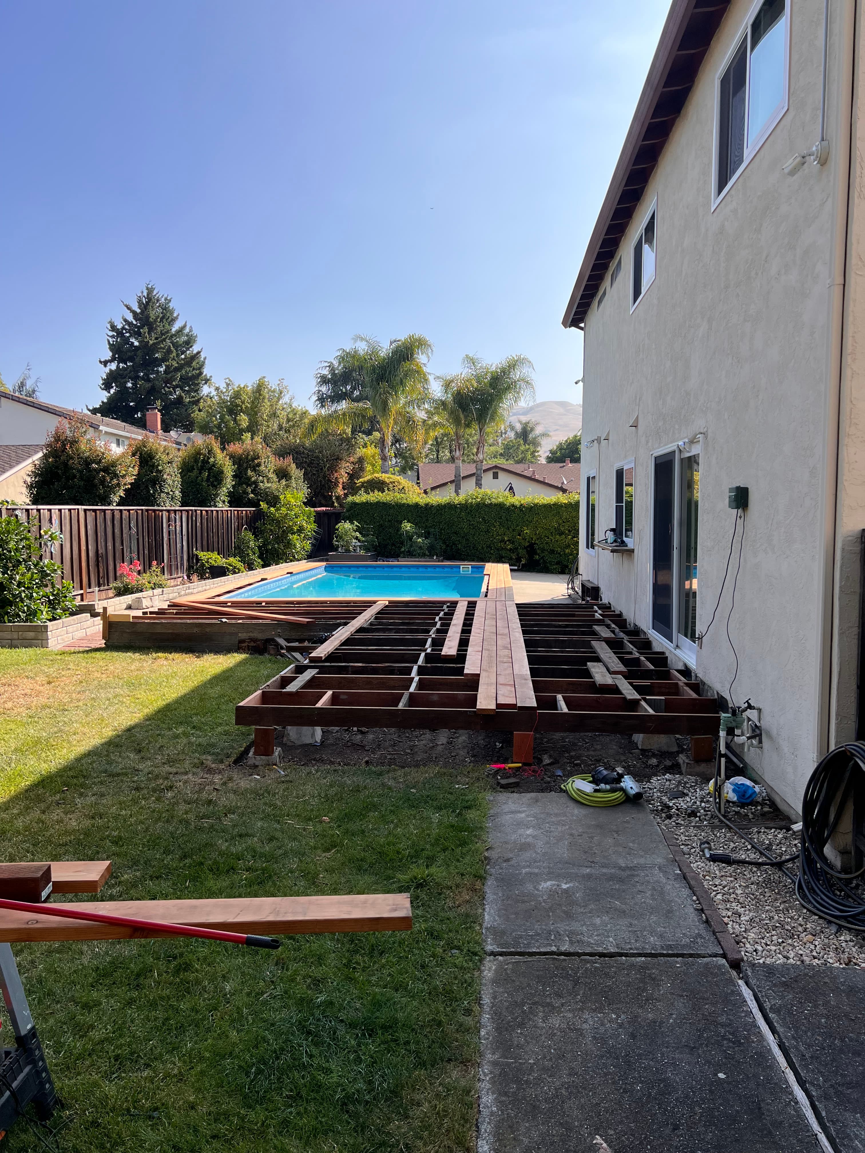 Redwood pool deck construction in progress next to backyard pool by Far West Builders